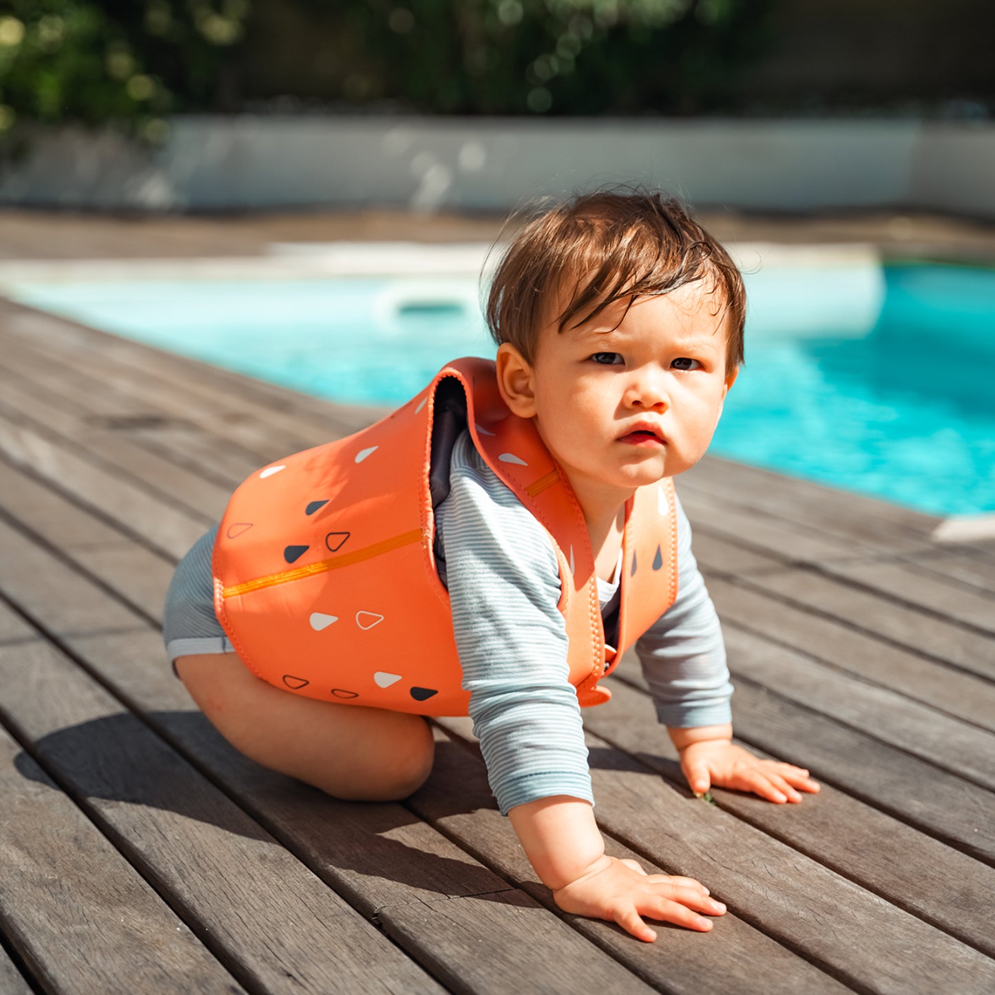 Chaleco flotante naranja BBLUV en bebé, en la piscina durante un día soleado