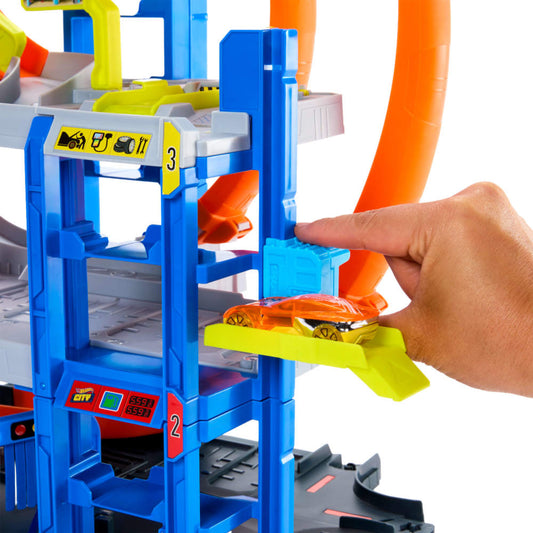 Pista de Hot Wheels, torre azul, manos manipulando coche naranja