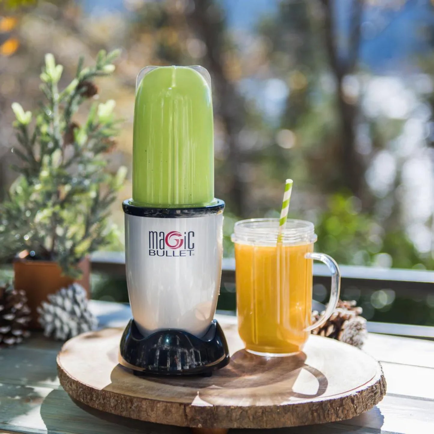 Licuadora Magic Bullet 11 piezas en uso con batido verde y vaso de jugo sobre una tabla de madera