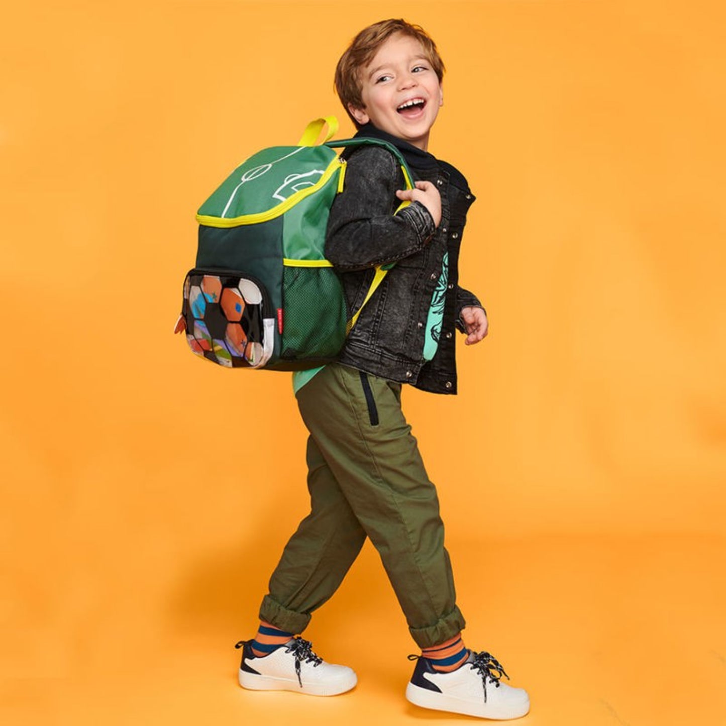 Mochila escolar verde con diseño divertido, niño feliz caminando