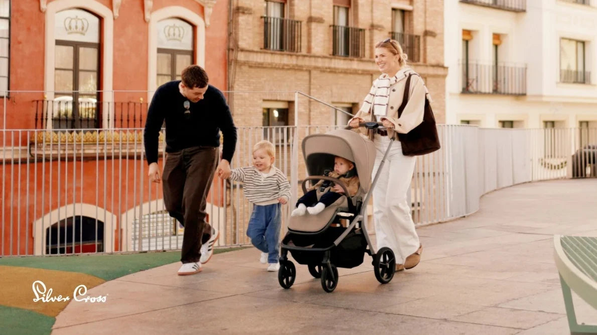 Carrito de bebe negro frente a una familia caminando por la calle