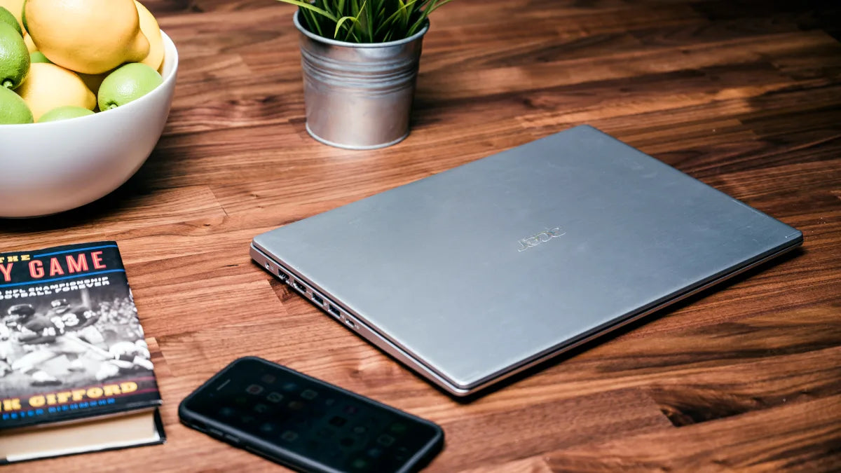 Ofertas laptops Lady Lee sobre un escritorio con frutas, un libro y un teléfono móvil