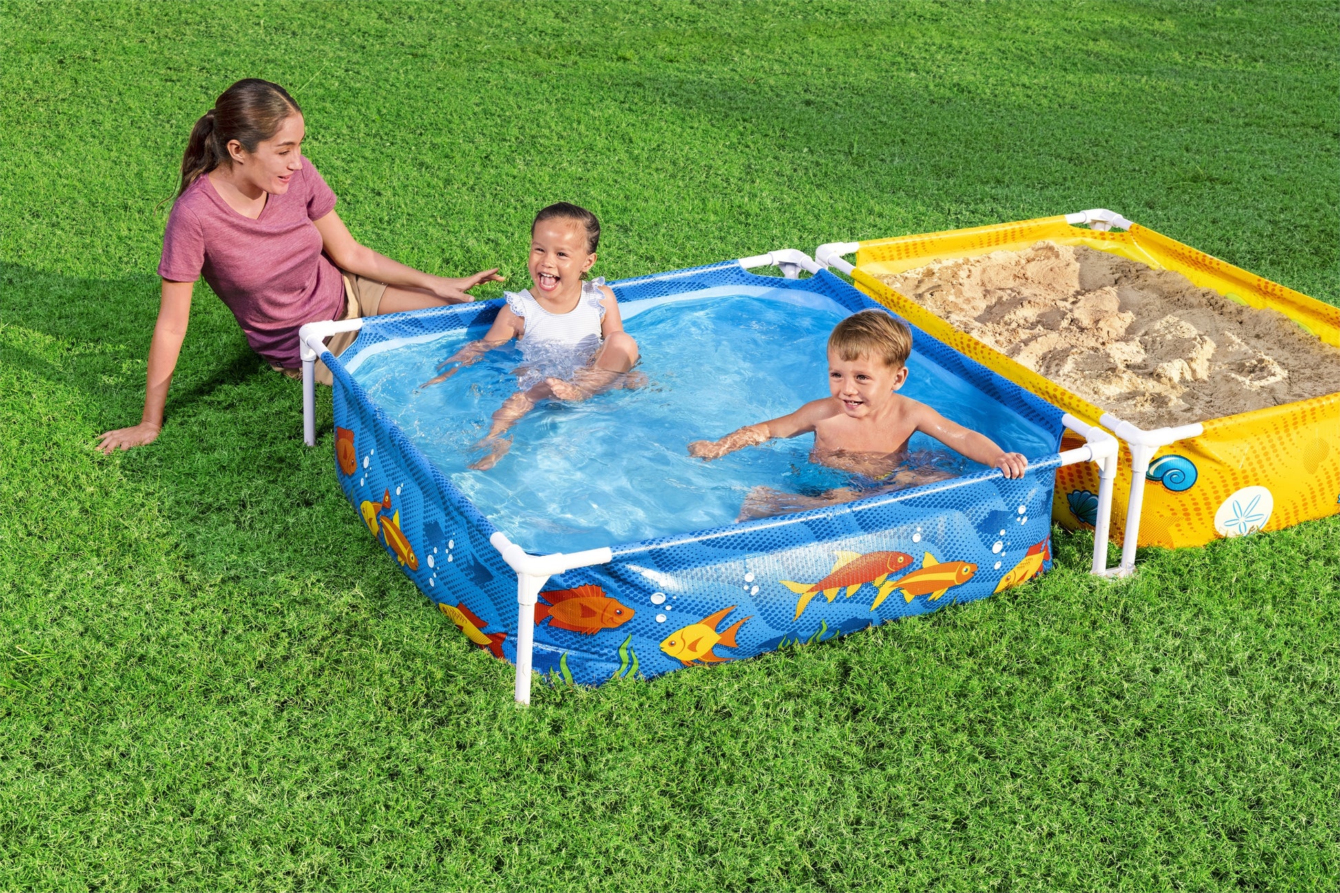 piscina infantil con tubos Bestway, niños felices jugando, césped verde