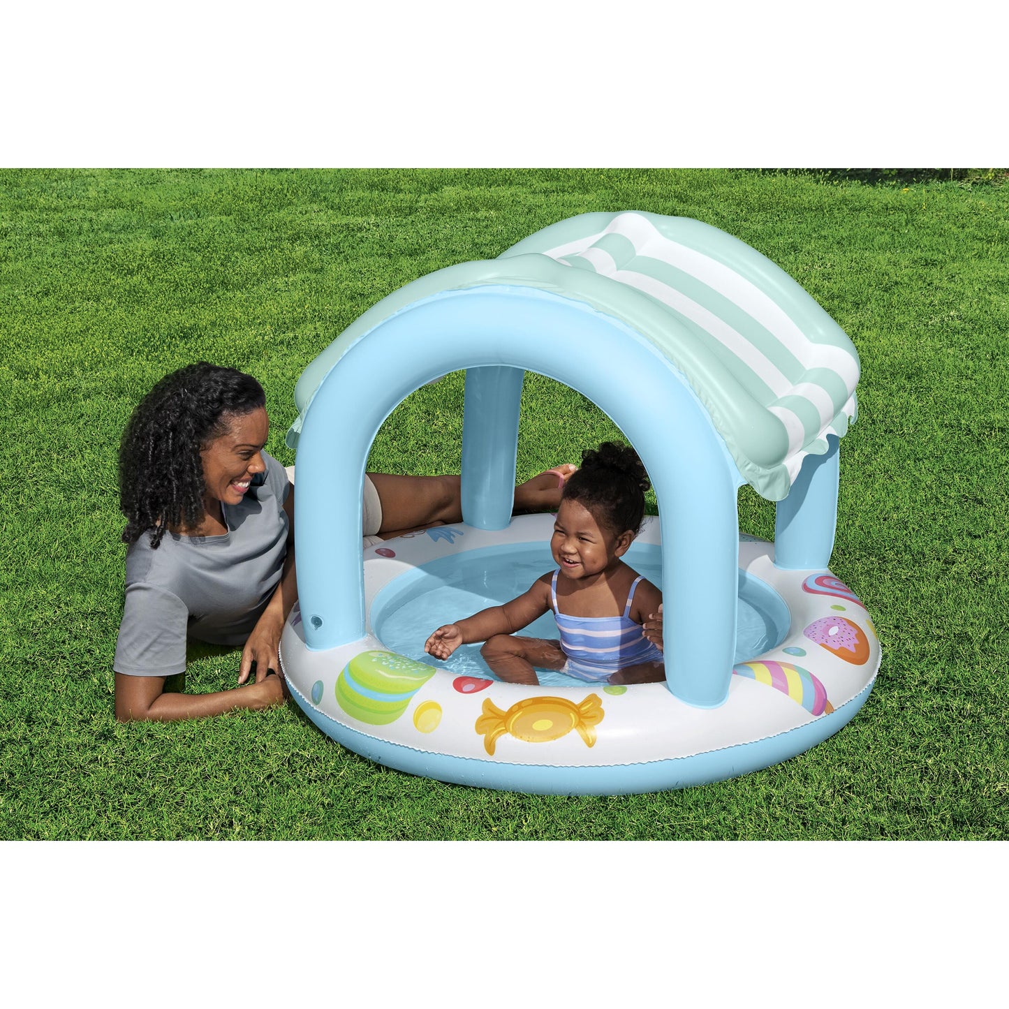 Piscina infantil con sombra azul, vista frontal en jardín, niño jugando bajo el toldo