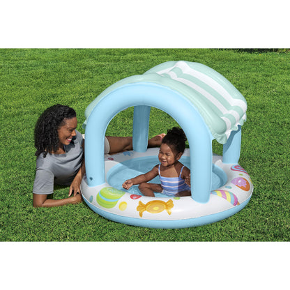 Piscina infantil con sombra azul, vista frontal en jardín, niño jugando bajo el toldo