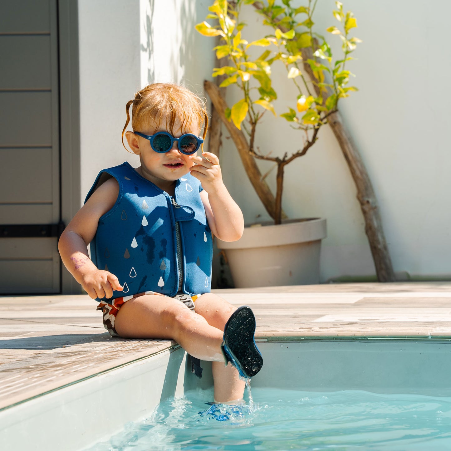 Chaleco azul BBLUV en niño, jugando junto a la piscina, soleado