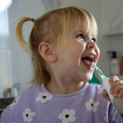 Cepillo de dientes infantil blanco, niña sonriendo, baño moderno