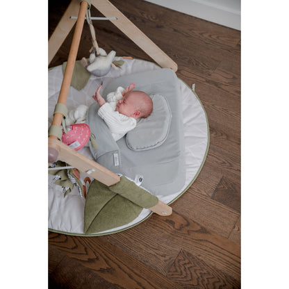Almohadas suaves grises en colchoneta para bebés, zona de juego cómoda