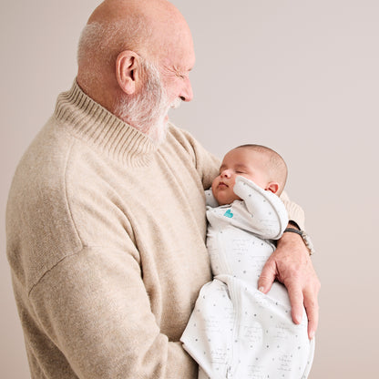 Envolvedor blanco de LOVE TO DREAM, bebé dormido en brazos de su abuelo