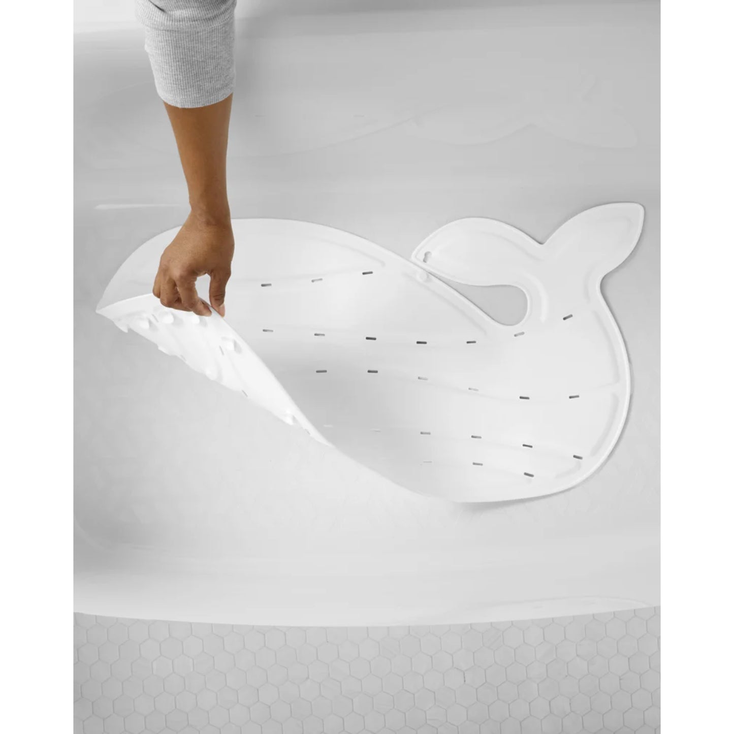 Alfombra blanca en forma de ballena para baño, vista desde arriba con mano levantándola