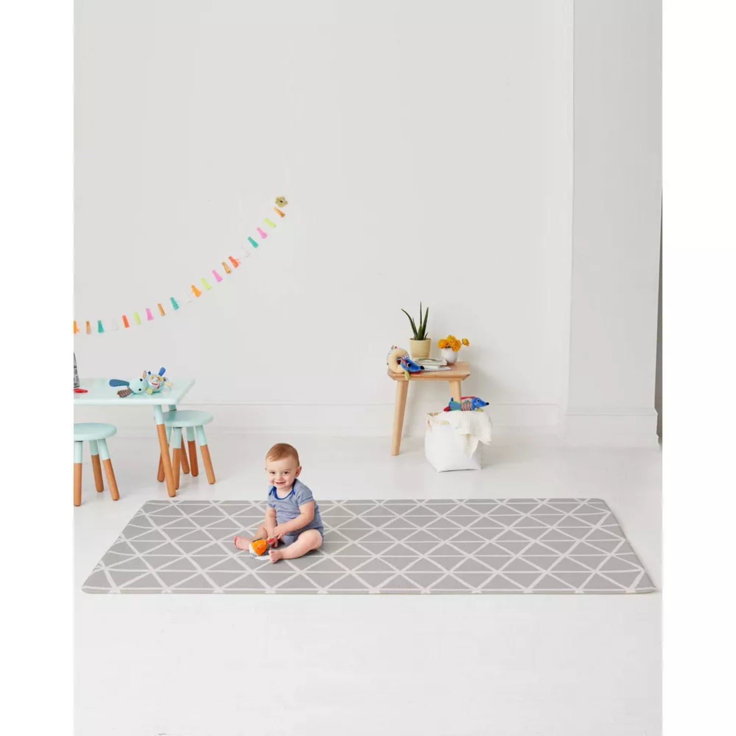 Alfombra gris SKIP*HOP, diseño geométrico, con niño jugando en sala