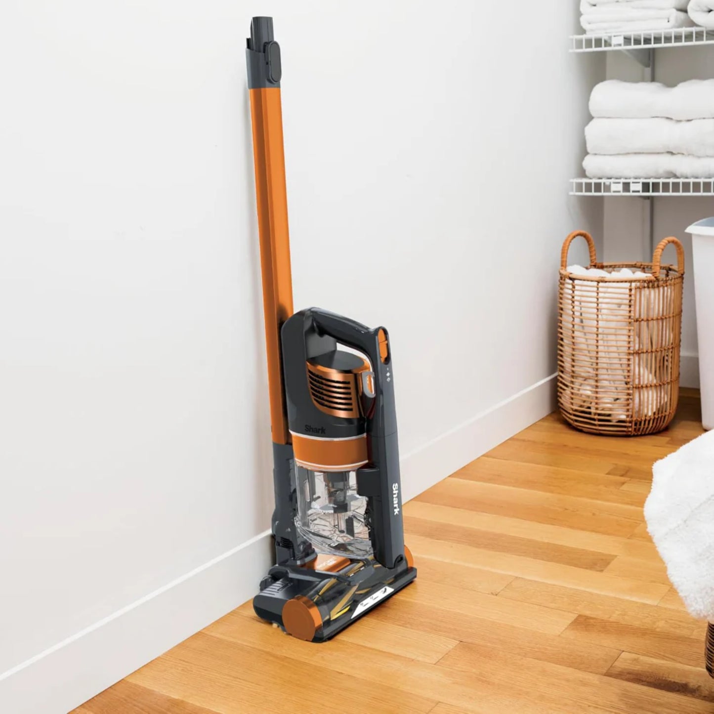 Aspiradora robot para mascotas modelo naranja apoyada en la pared, en habitación limpia