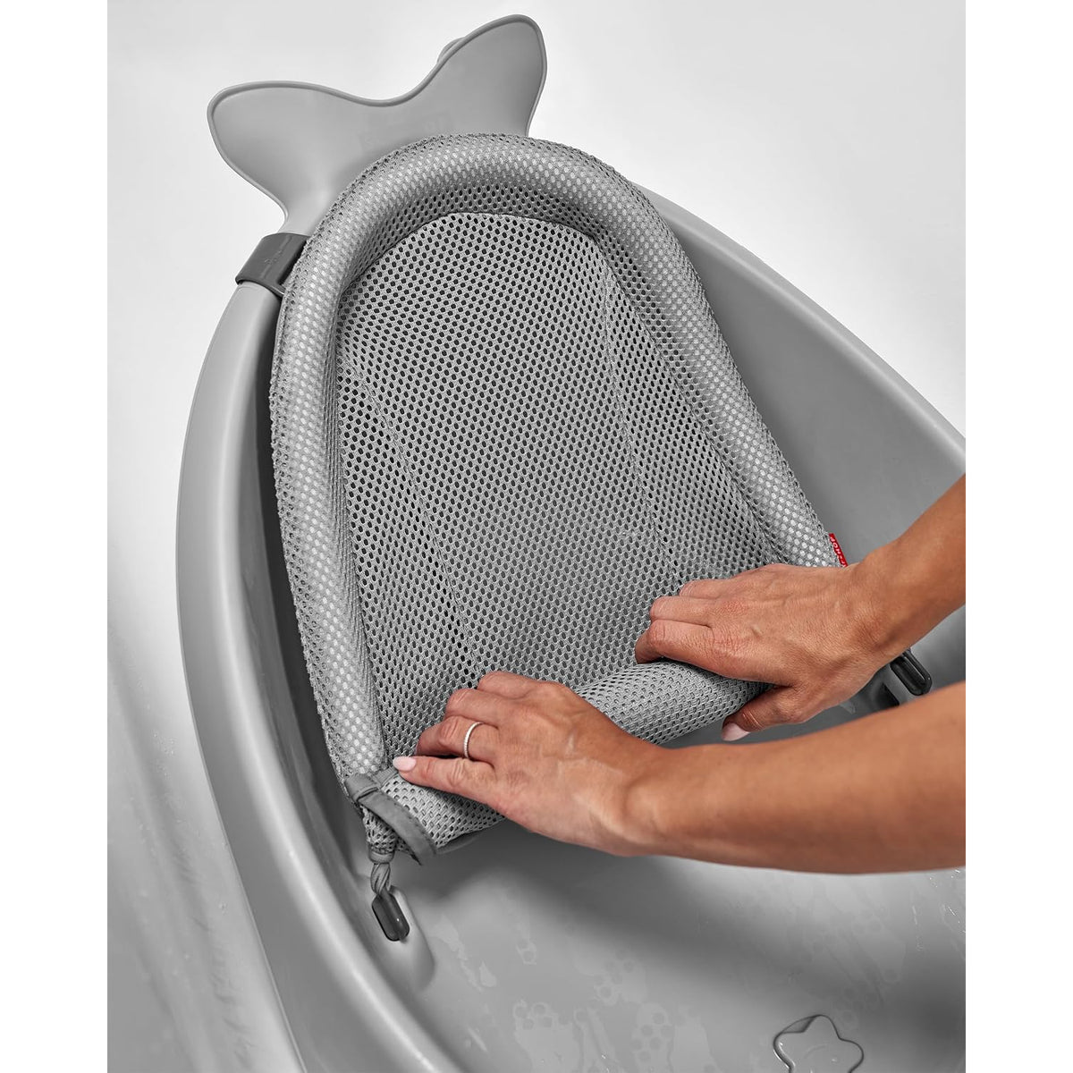 Bañera con hamaca para bebe gris, vista de manos ajustando la hamaca