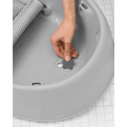 Bañera con hamaca para bebe gris, vista lateral con mano ajustando el tapón