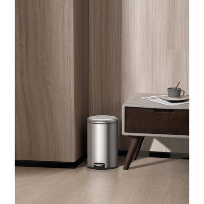 Basurero metálico con pedal EKO modelo LL02 en acero inoxidable junto a mesa auxiliar en habitación moderna