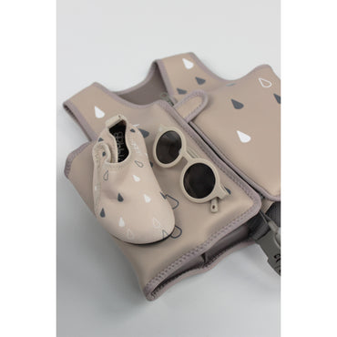 chaleco beige con gafas de sol y zapatitos, ideal para actividades al aire libre