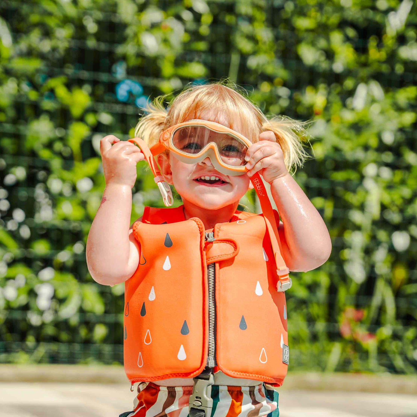 Chaleco salvavidas naranja para niños, vista frontal en piscina, niño feliz con gafas de sol