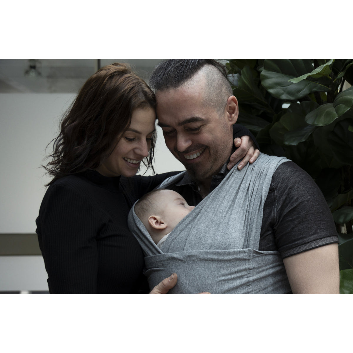 Portabebés gris BBLUV, familia sonriendo con bebé, ambiente acogedor