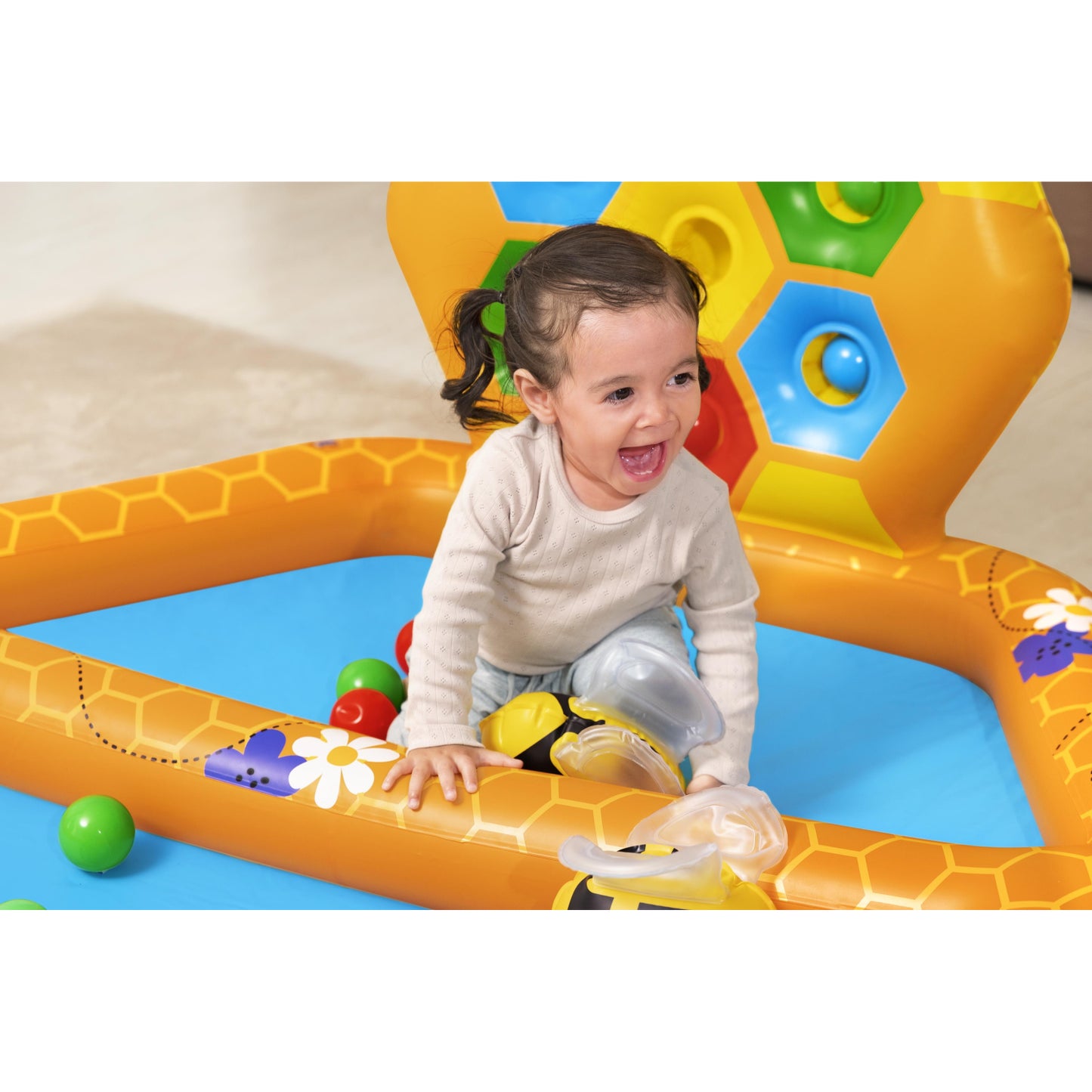 Niña jugando en piscina Bestway Beehive niños, color anaranjado y azul con pelotas de colores