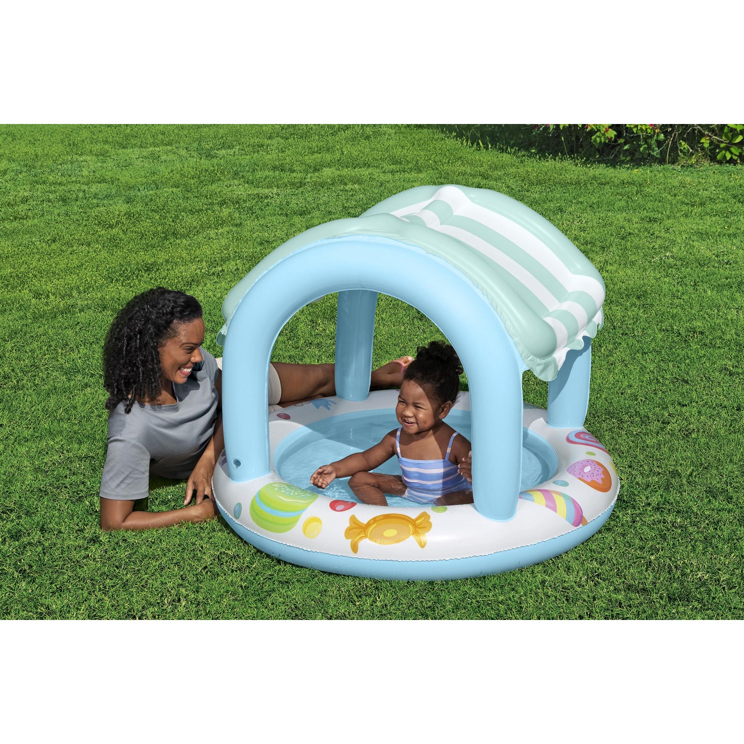 piscina infantil con sombra azul, vista lateral en césped, diversión bajo el sol