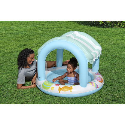 piscina infantil con sombra azul, vista lateral en césped, diversión bajo el sol