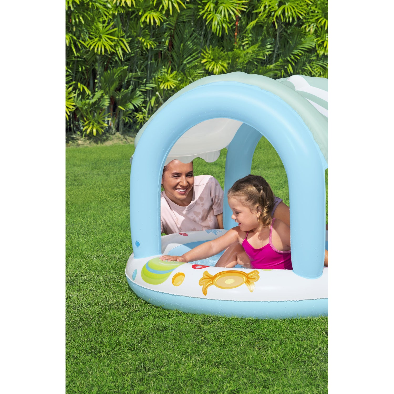 piscina infantil con sombra azul, vista lateral en jardín con niños disfrutando
