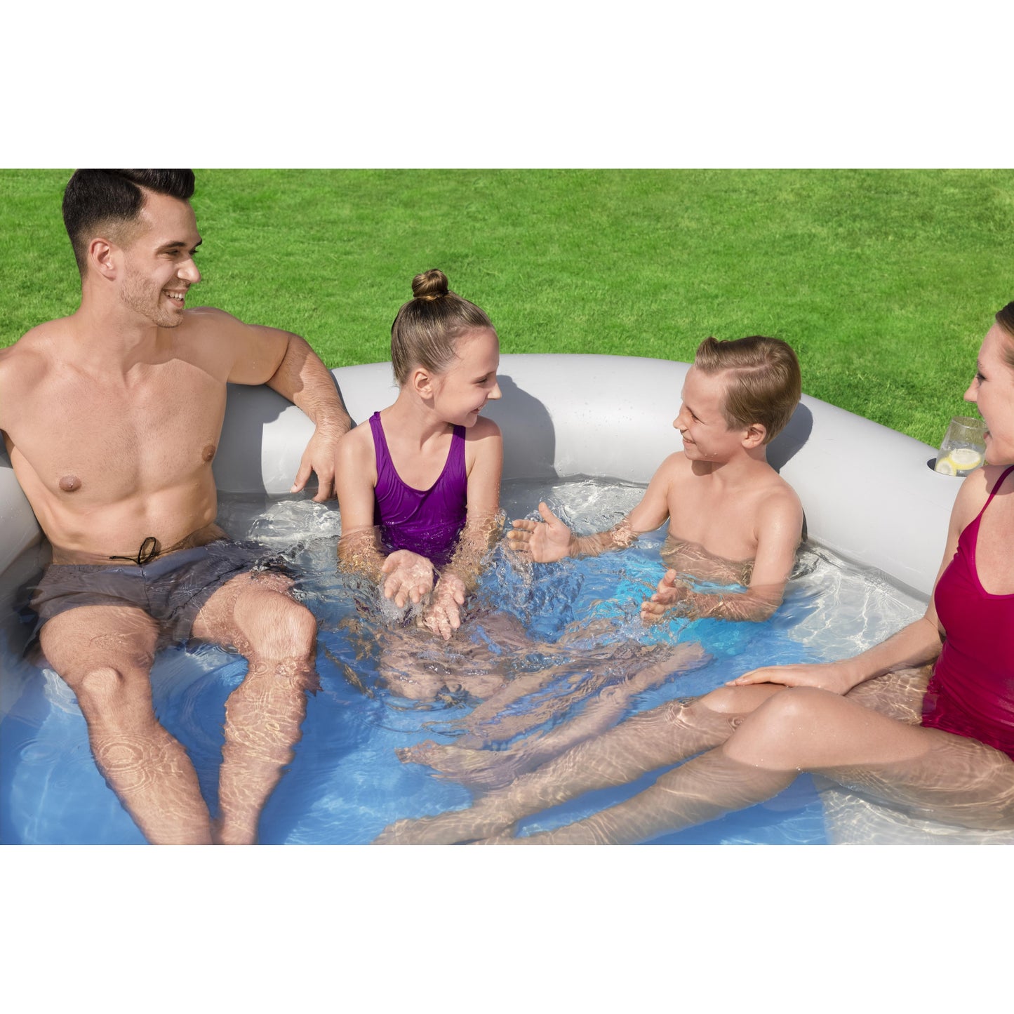 Piscina inflable familiar Bestway gris, vista lateral con niños y adultos disfrutando en el agua