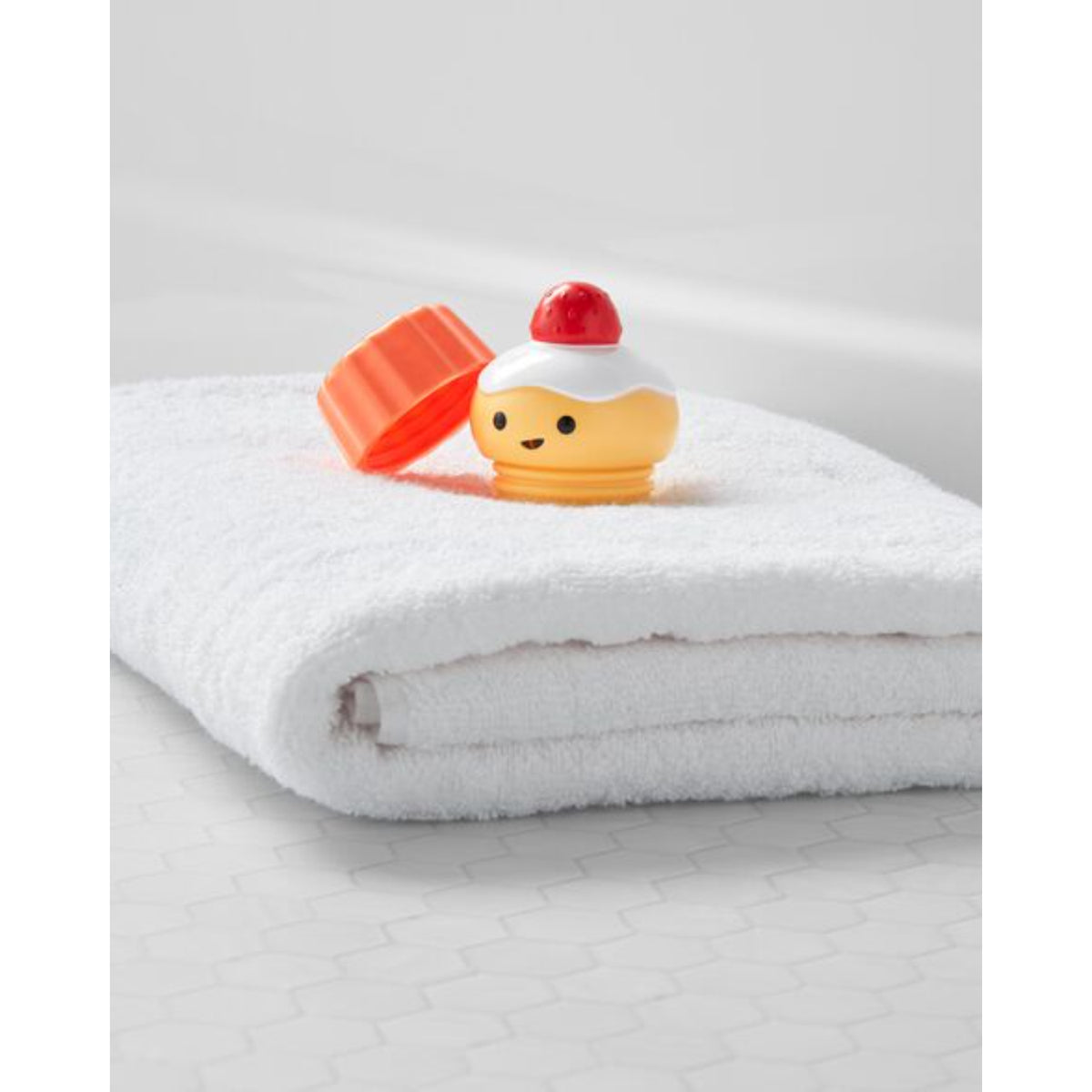 Juguete de baño burbujas color amarillo y rojo sobre toalla blanca