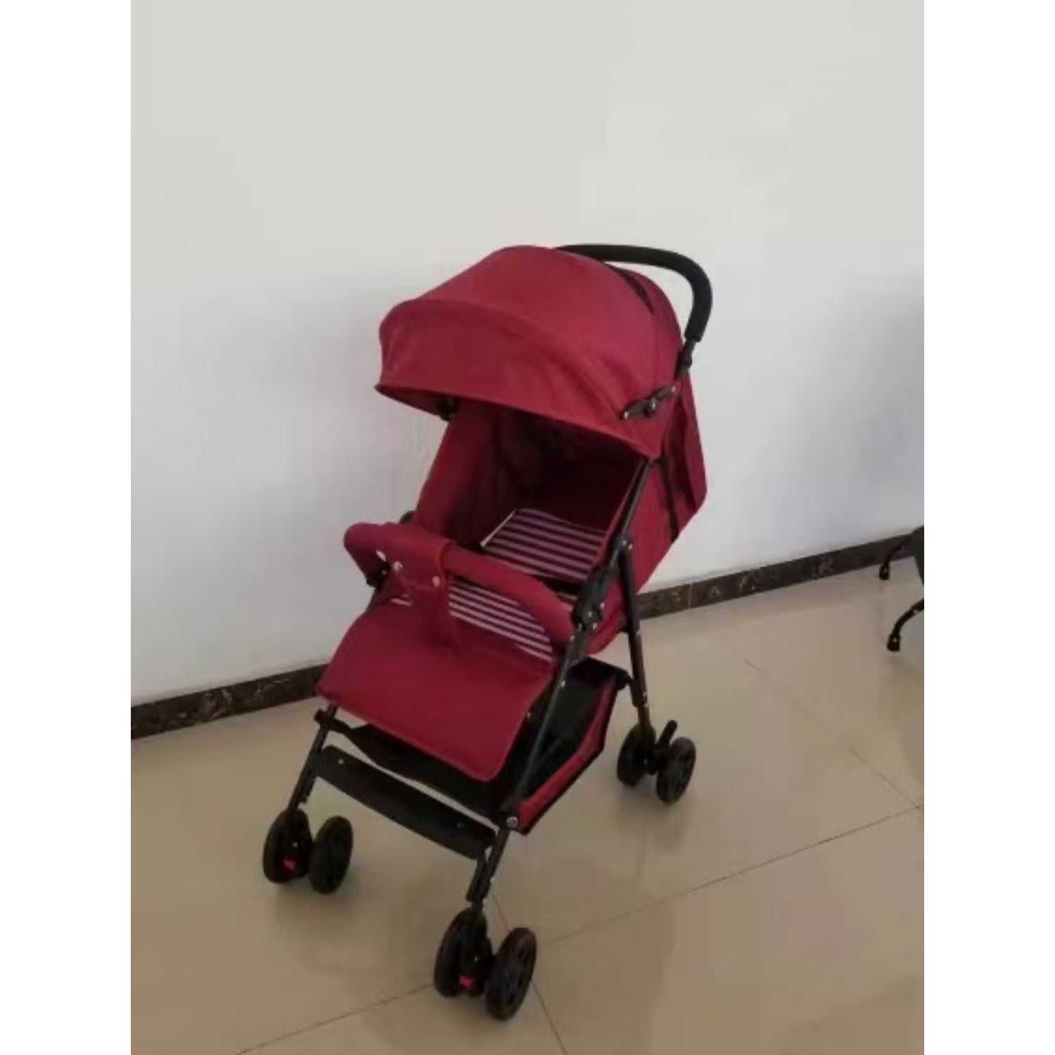 Coche rojo KIDILO de paseo, visto de lado en ambiente interior