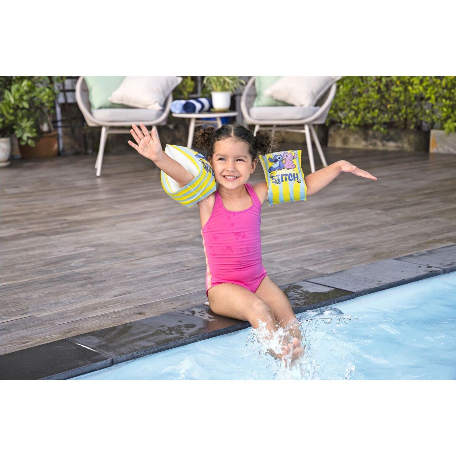 Niña feliz con flotadores Disney Bestway 23x15cm mientras juega junto a la piscina