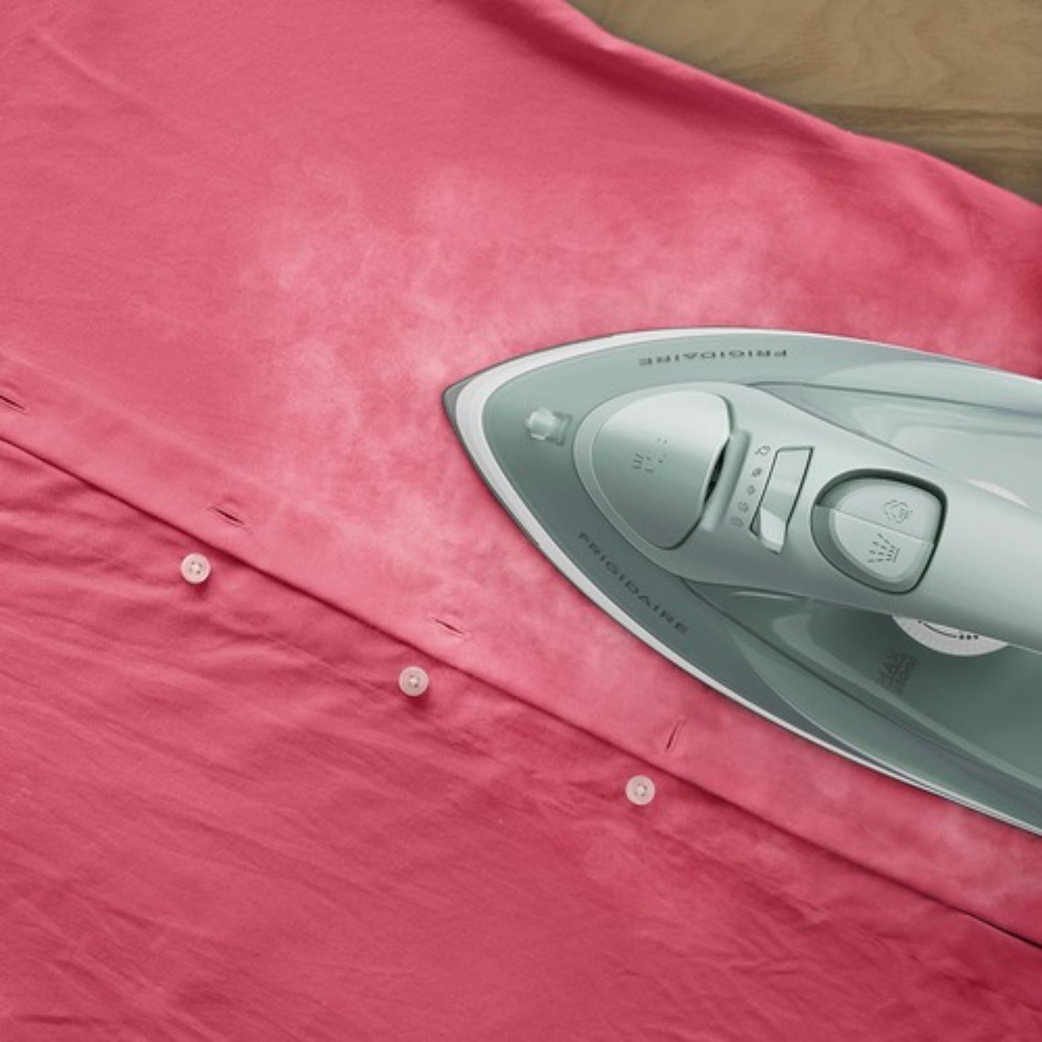 plancha a vapor 1200W gris, vista superior sobre camisa rosa