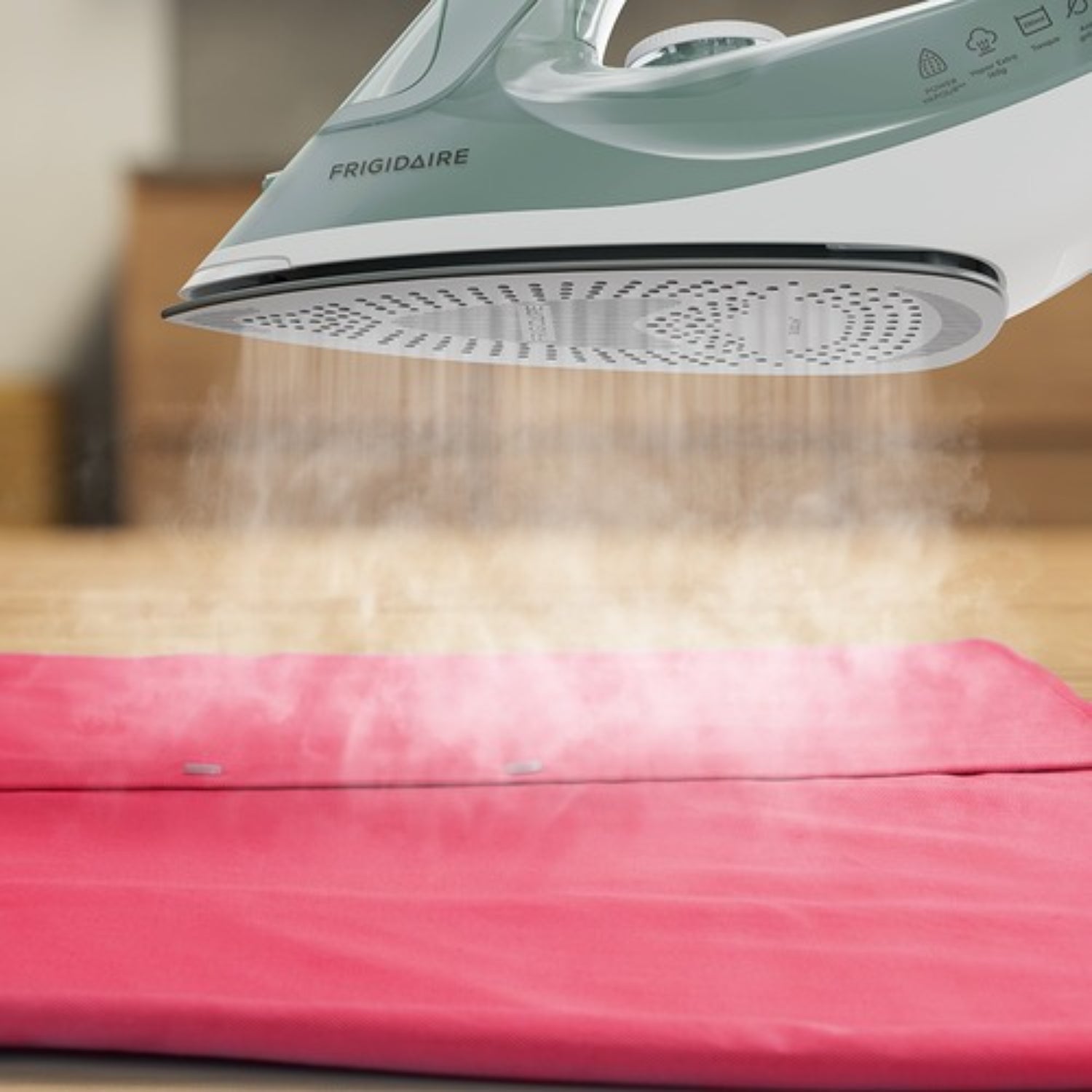 Plancha a vapor 1200W Frigidaire en acción sobre tela roja