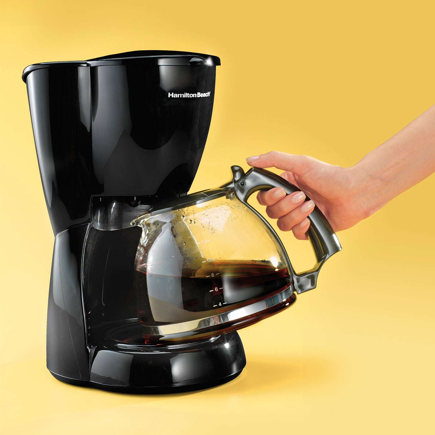 cafetera eléctrica negra, vista lateral, mano sirviendo café