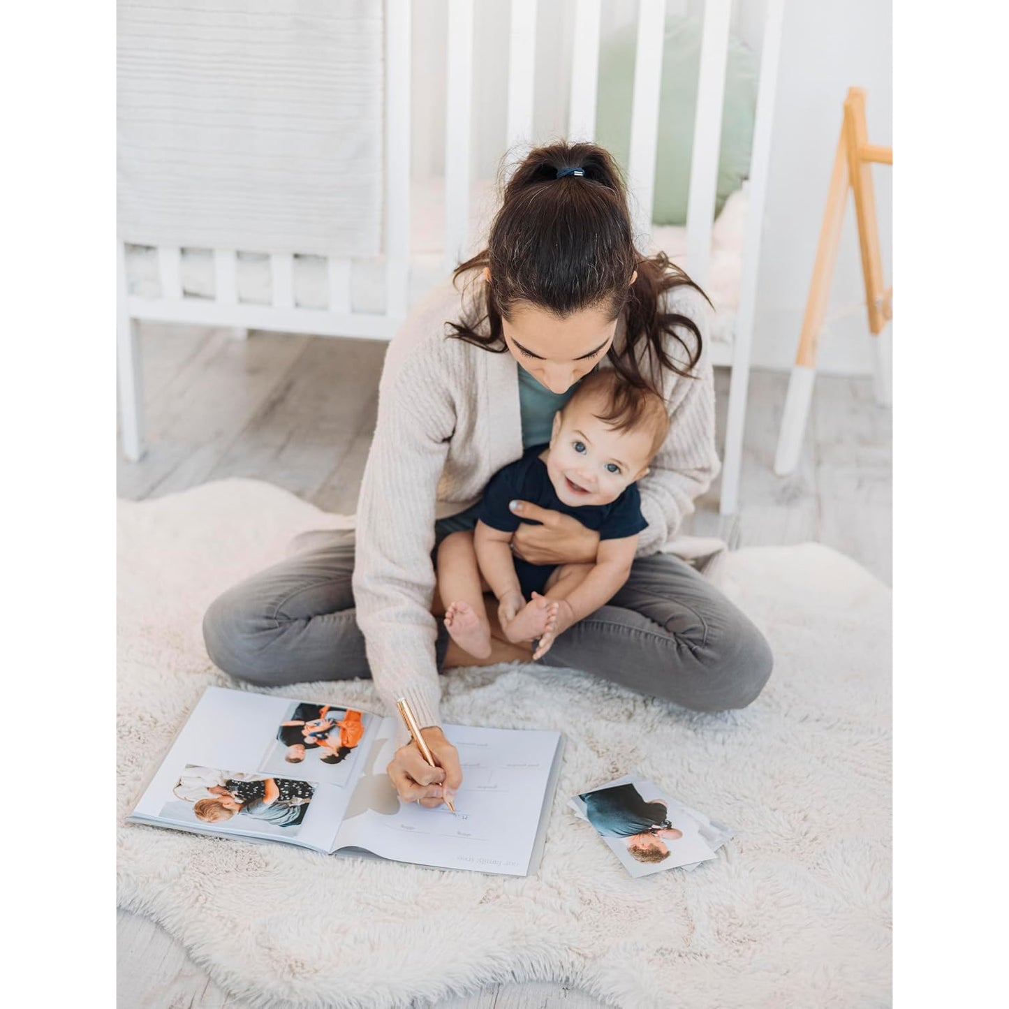 Madre con bebé escribiendo en álbum fotográfico, decoración cálida y acogedora