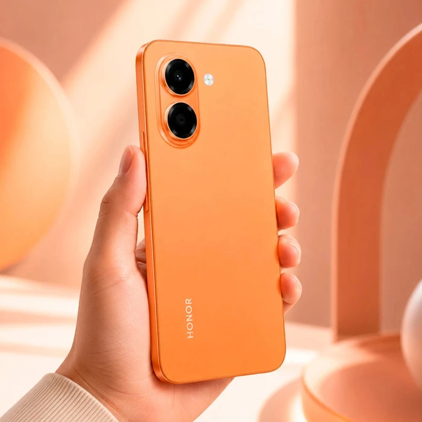 teléfono HONOR naranja, vista trasera en mano, fondo minimalista