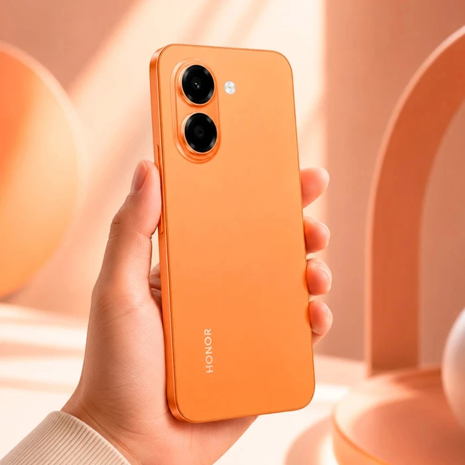 teléfono HONOR naranja, vista trasera en mano, fondo minimalista