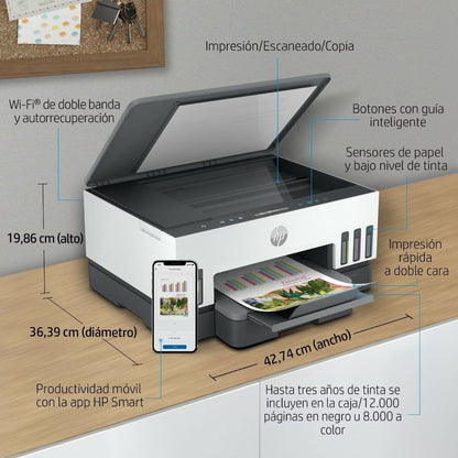 Impresora HP multifuncional blanca, vista frontal en escritorio con teléfono móvil