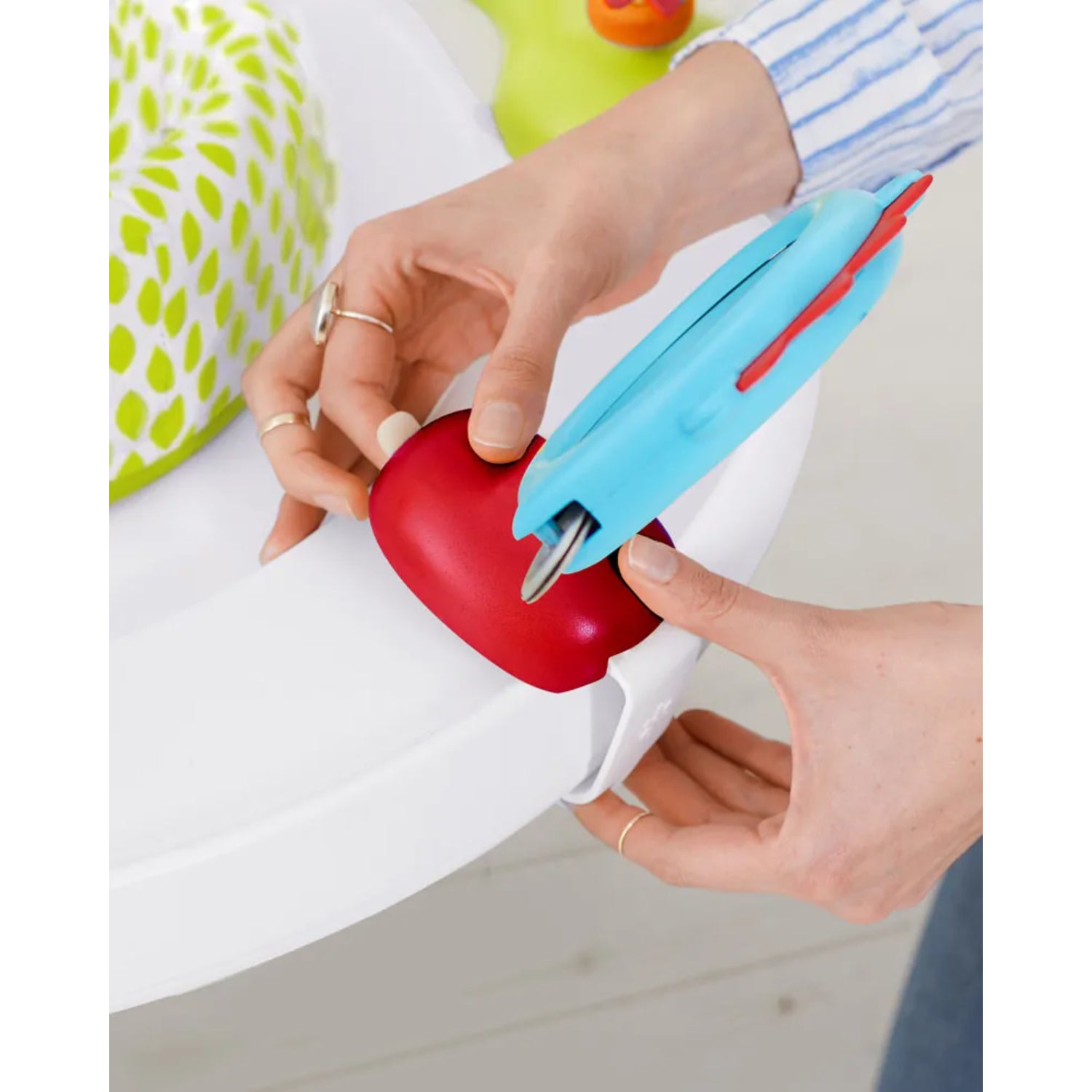 Utensilio de comida azul y rojo, vista en mano, contexto de alimentación para niños