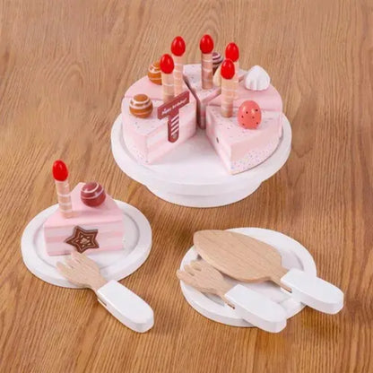 Tarta de cumpleaños de madera en tonos rosas, con velas y platos de juguete