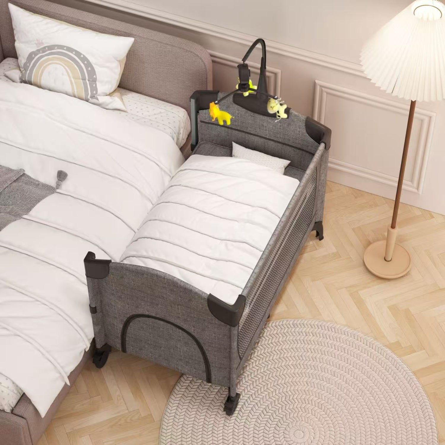 Cuna portátil KIDILO gris vista lateral con juguetes colgantes en habitación