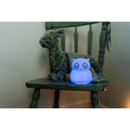Lámpara búho azul en una silla con peluche verde en habitación