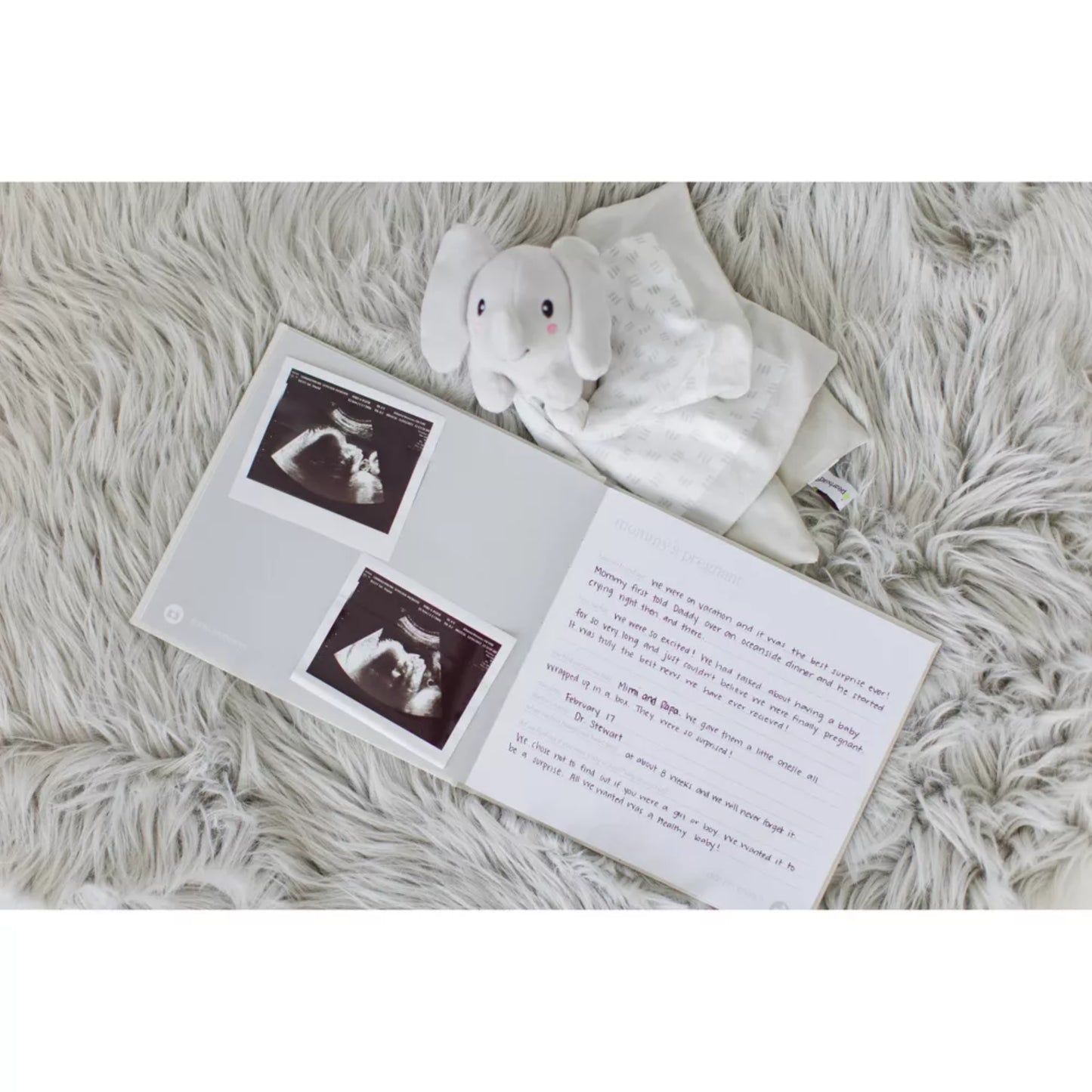 libro de recuerdos blanco abierto con fotos de ultrasonido y un peluche de elefante