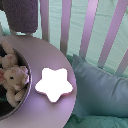 Luz noctur en forma de estrella blanca sobre mesa, habitación infantil con juguetes