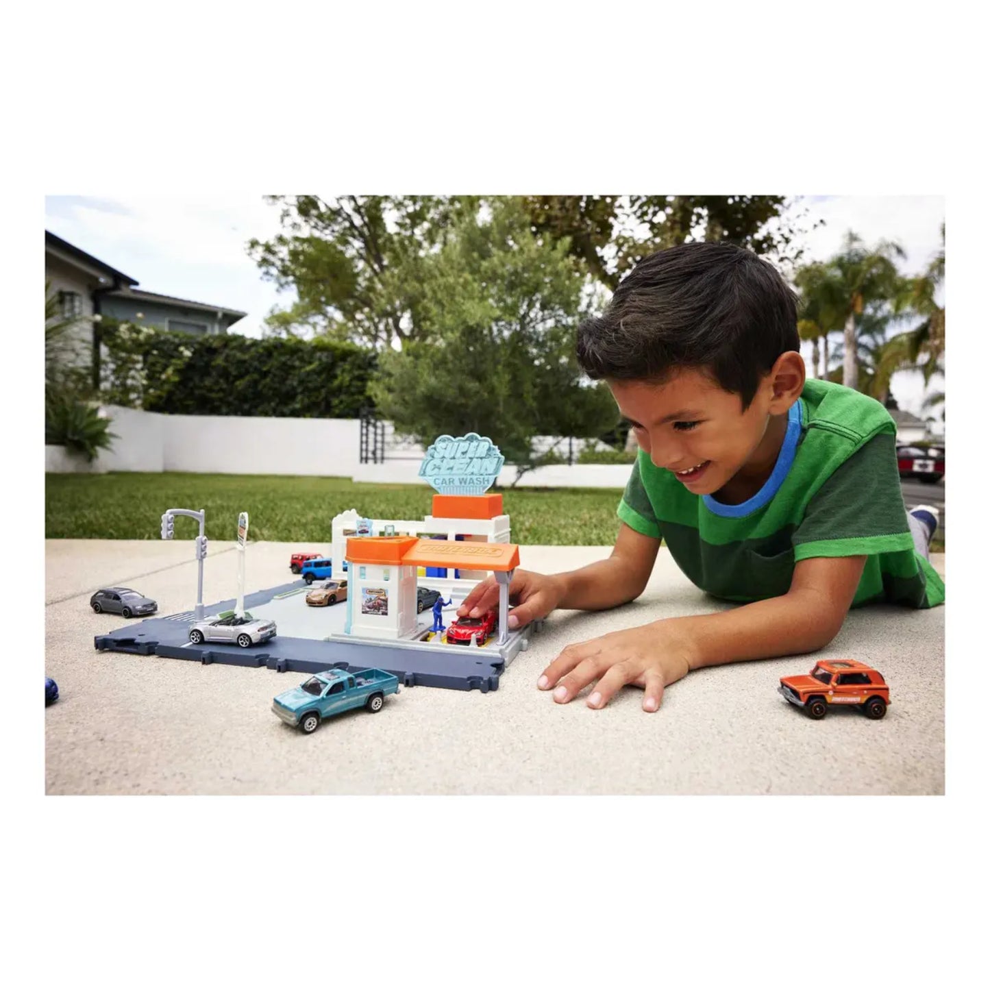Niño jugando con juego de coches LL0308 de Mattel, vista frontal en el patio