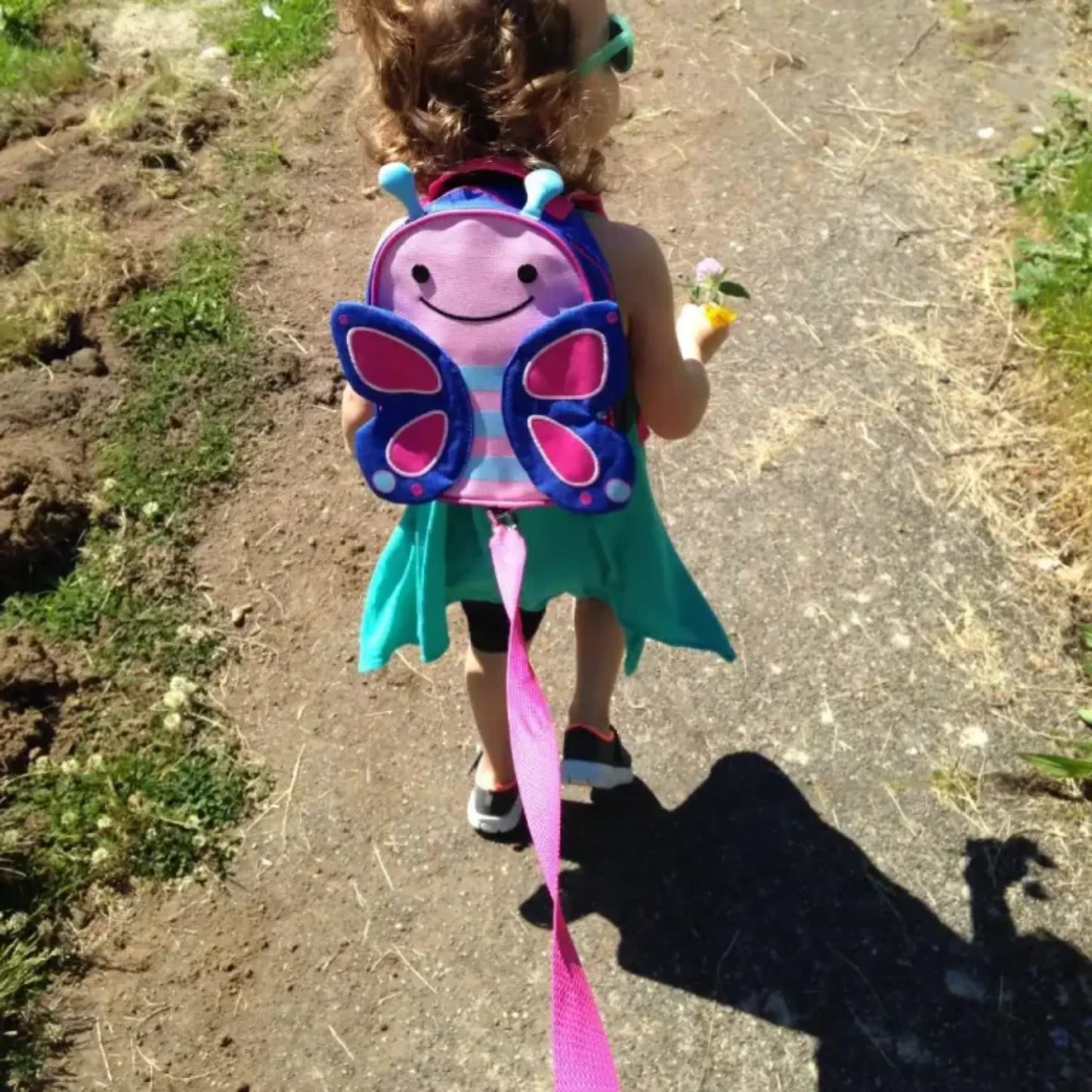 mochila infantil mariposa rosa, vista trasera, niña caminando por el campo