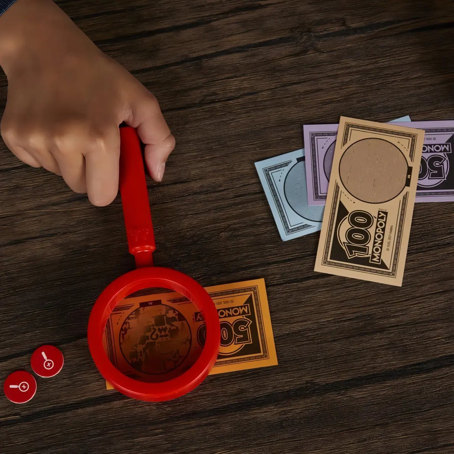 Mano sosteniendo un billete del casino monopoly sobre dinero de juego en mesa de madera