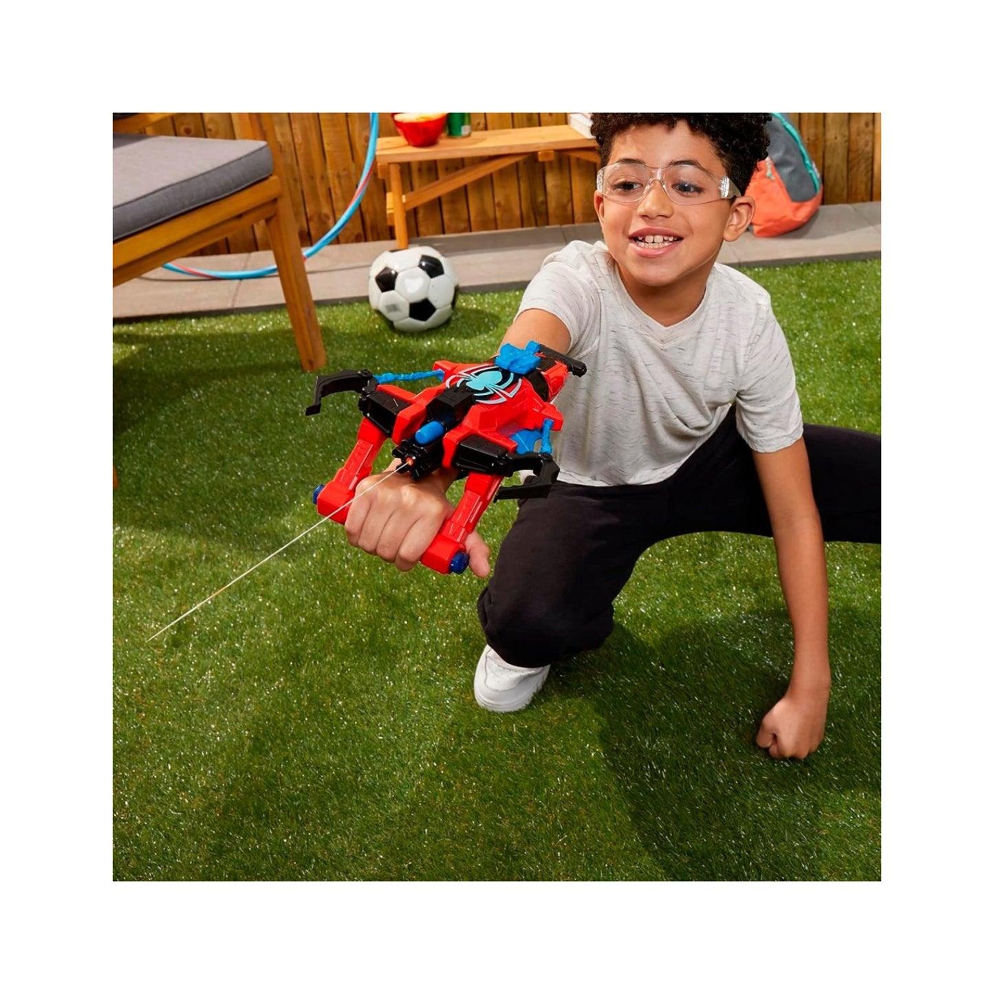 Pistola de agua roja y negra, niño jugando en el jardín con balón