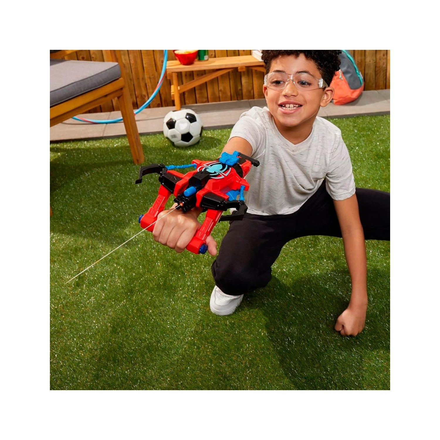 Pistola de agua roja y negra, niño jugando en el jardín con balón