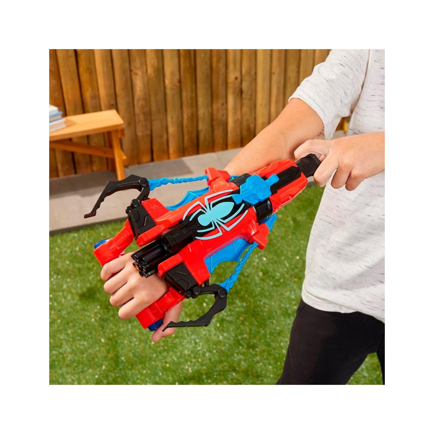 Pistola de agua roja y azul en la mano, vista lateral en jardín