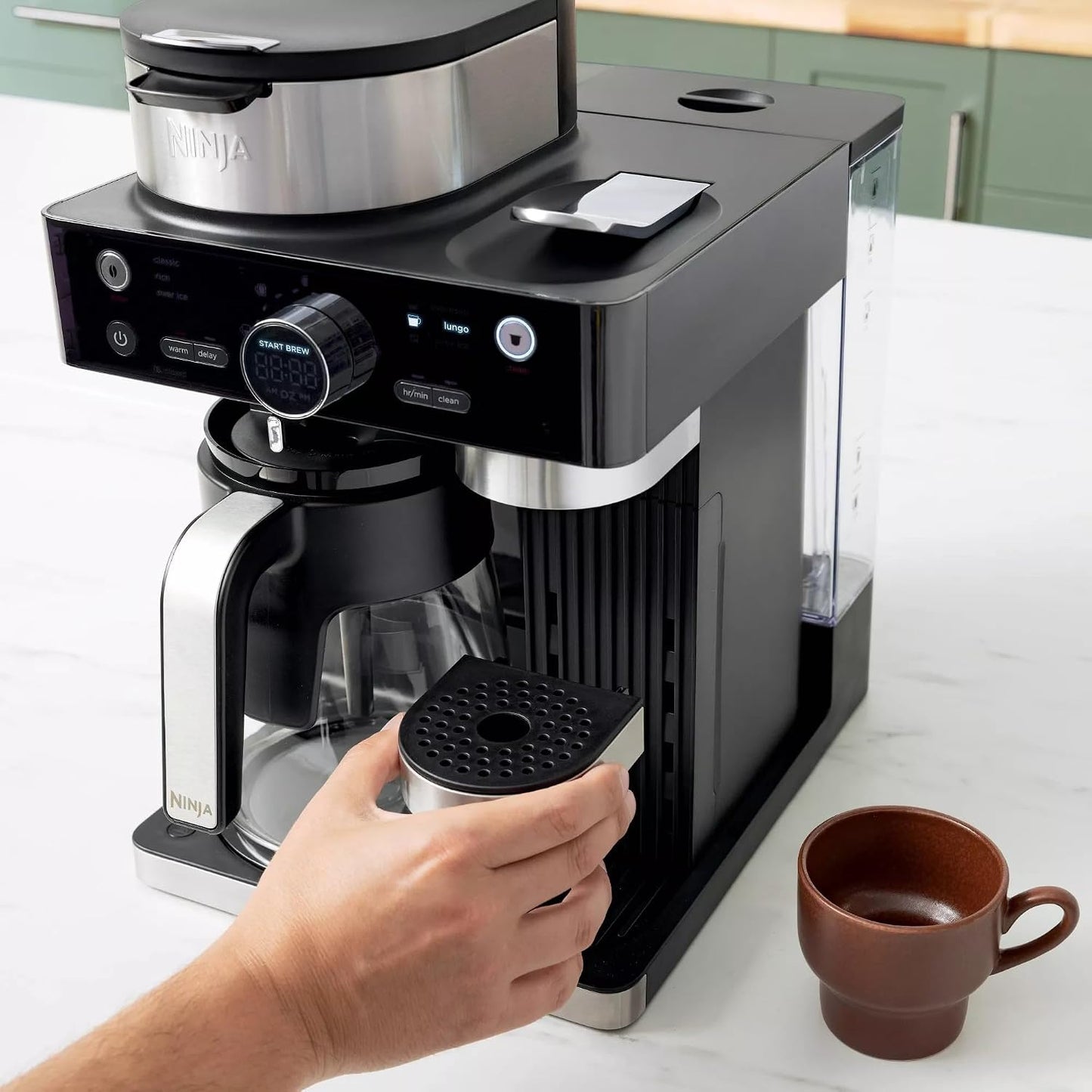 Cafetera Ninja negra, vista frontal con café y taza al lado